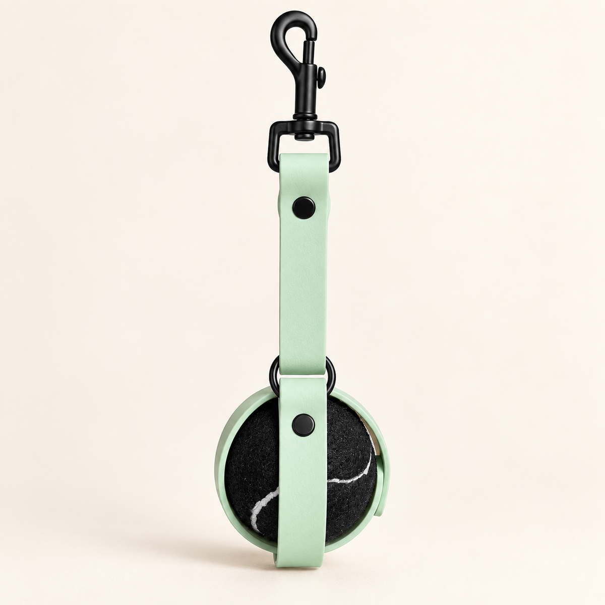 Mint green BioThane dog ball holder with black hardware and a tennis ball